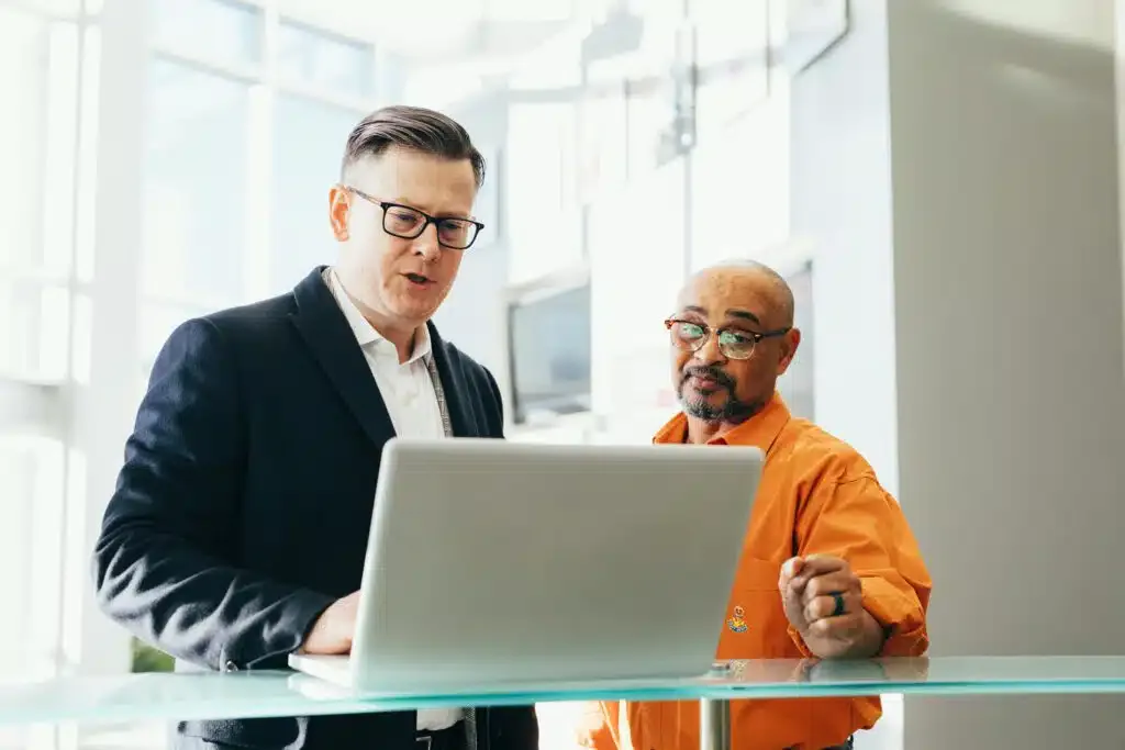 pexels photo 2182973 2182973 Two business professionals engaged in a collaborative discussion over a laptop in a modern office setting.